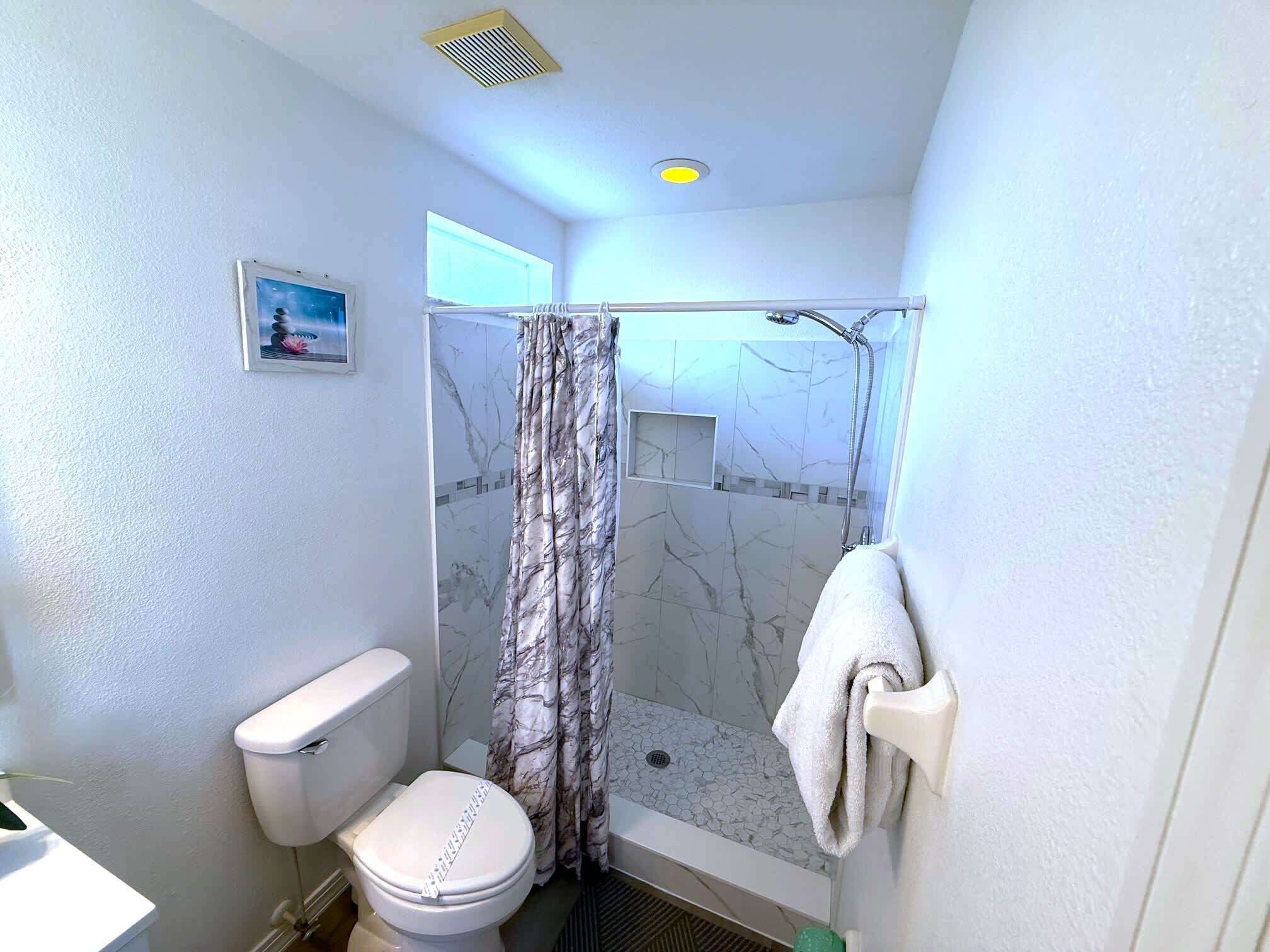 Une petite salle de bain comprenant des toilettes, une douche et un porte-serviettes.