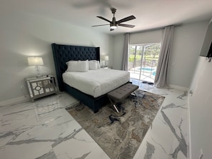 A bedroom with a bed, a nightstand, a ceiling fan, and a view of the outdoors. - Beautifully Remodeled Home - Southen Dunes Golf Course Views (Haines City)