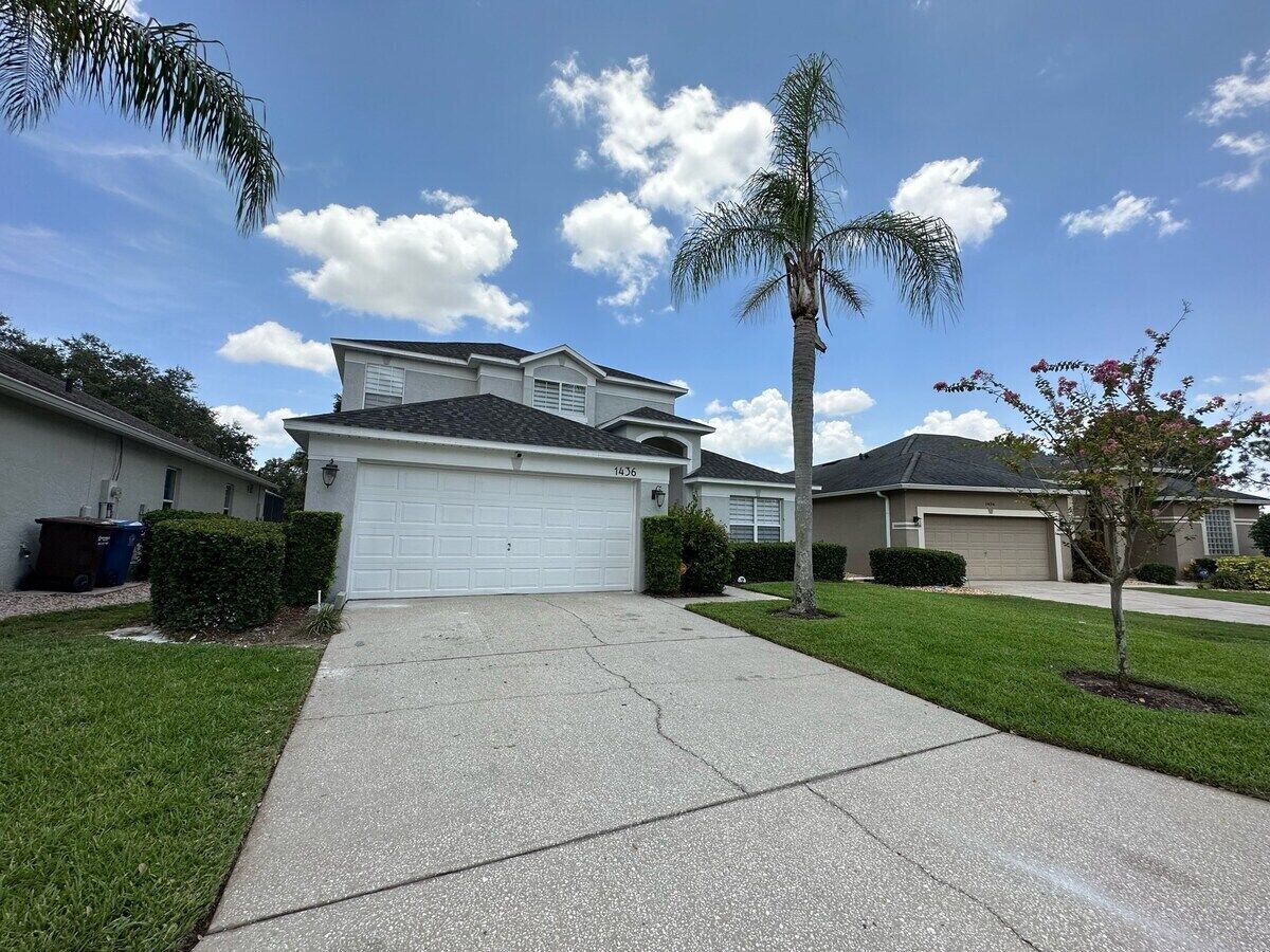 A residential house with a garage, a driveway, and a well-maintained lawn.