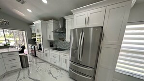 A modern kitchen with white cabinetry, a stainless steel refrigerator, and a marble floor. - Beautifully Remodeled Home - Southen Dunes Golf Course Views (Haines City)