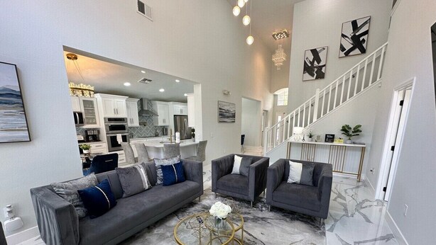 A modern living room with a grey sofa set, a coffee table, and a staircase leading to a second floor. - Beautifully Remodeled Home - Southen Dunes Golf Course Views (Haines City)