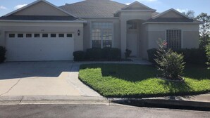 A two-story house with a garage, a front porch, and a well-maintained lawn. - Private, Large Pool Villa, Southern Dunes, Golf Views, Large Pool Deck (Haines City)