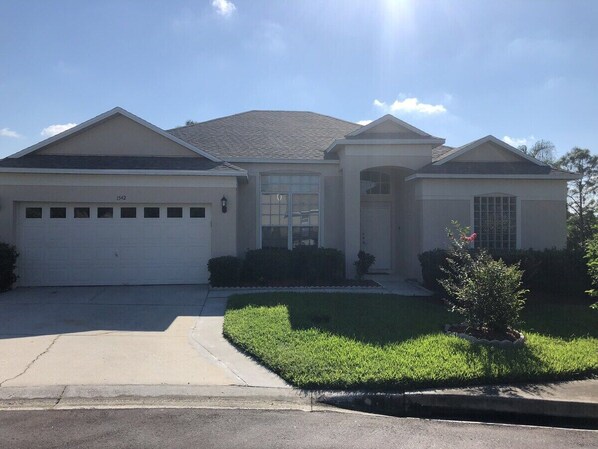 A two-story house with a garage, a front porch, and a well-maintained lawn. - Private, Large Pool Villa, Southern Dunes, Golf Views, Large Pool Deck (Haines City)