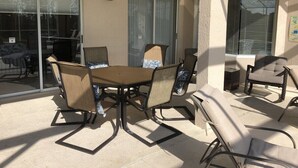 A patio area with a table and chairs, a ceiling fan, and a view through a glass door. - Private, Large Pool Villa, Southern Dunes, Golf Views, Large Pool Deck (Haines City)