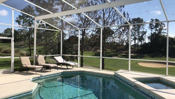 A pool with clear water, surrounded by a covered area with lounge chairs. - Private, Large Pool Villa, Southern Dunes, Golf Views, Large Pool Deck (Haines City)