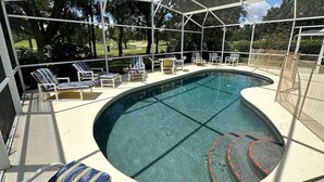 A swimming pool with a covered area and lounge chairs. - Modern, Fully Updated Southern Dunes Home - Golf Course Views (Haines City)