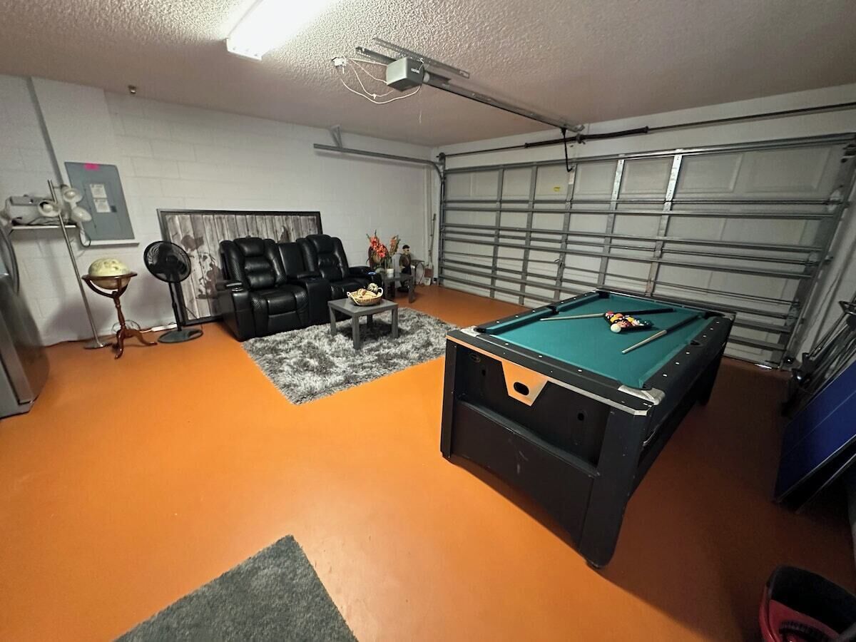 A room with a pool table, a sofa, and a fan.