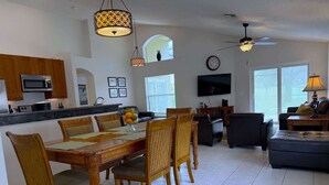 A spacious living area with a dining table, chairs, a sofa, and a TV. - South Facing Golf Course Views, Southern Dunes Villa (Haines City)