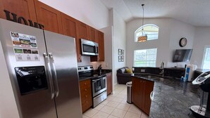 A modern kitchen with stainless steel appliances, wooden cabinets, and a granite countertop. - South Facing Golf Course Views, Southern Dunes Villa (Haines City)