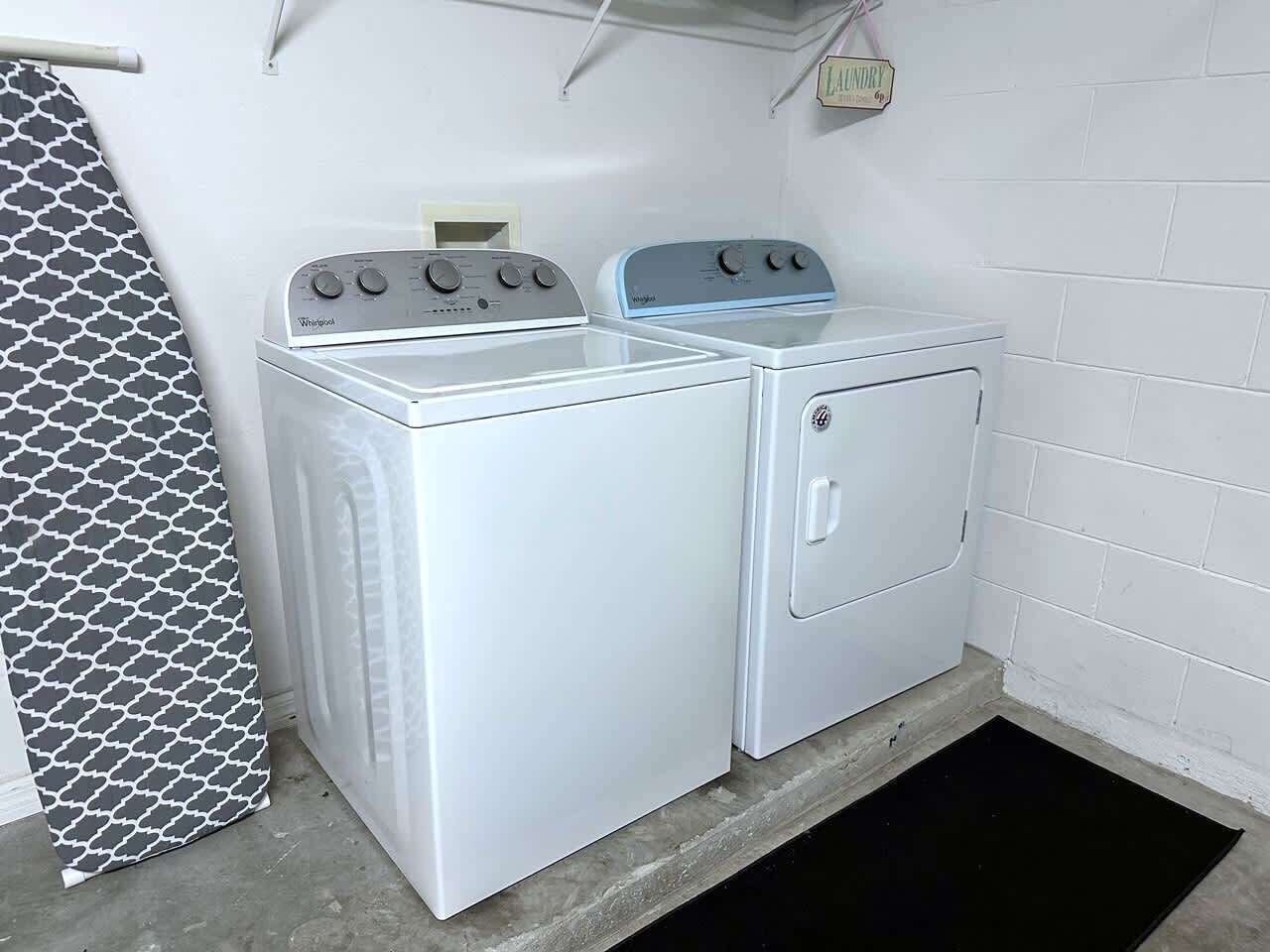 A laundry room with two washing machines and a drying rack.