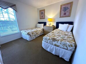 A hotel room with two beds, a nightstand, a lamp, and two framed pictures on the wall. - South Facing Pool Villa on the Golf Course (Haines City)