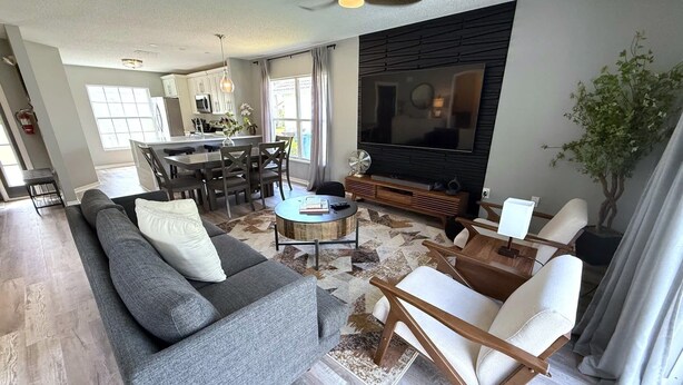 A modern living room with a gray sofa, a coffee table, and a TV. - Updated Southern Dunes Pool Home (Haines City)