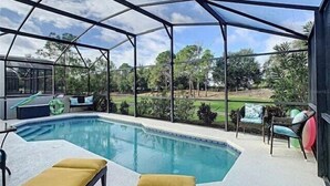 Piscina cubierta al aire libre con vistas a un jardín ajardinado y árboles.