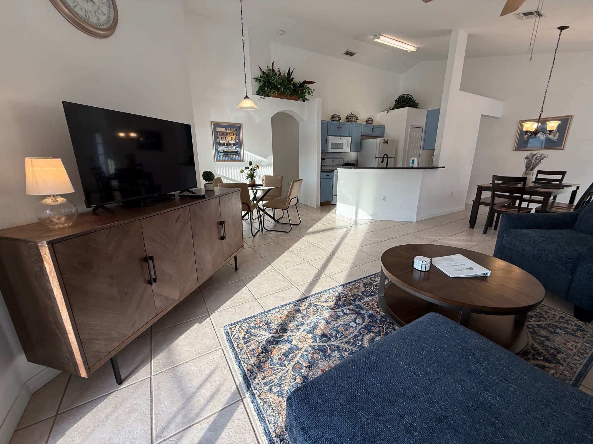 En moderne stue med tv, sofa, sofabord og spiseplads.