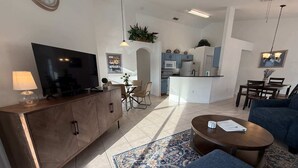 Una sala de estar moderna con televisor, sofá, mesa de centro y comedor.