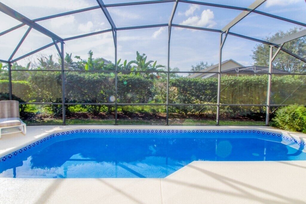 A covered swimming pool with a blue interior, surrounded by a metal frame and a white deck.
