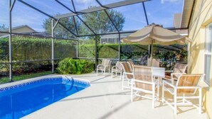 Ein überdachter Poolbereich im Freien mit Liegestühlen und Sonnenschirmen.