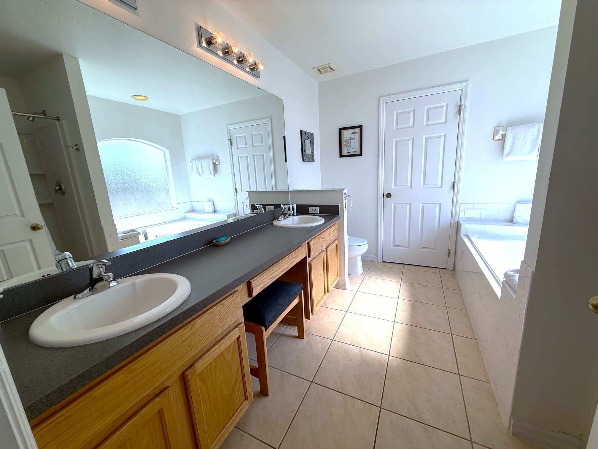 Ein Badezimmer mit zwei Waschbecken, einem großen Spiegel und einer Toilette.