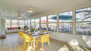 A bright dining area with a large table, yellow chairs, and a view of the outside through large windows. - Lakefront Home w/ Private Dock in Graford! (Graford)