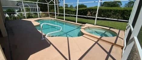 Zona de piscina con cerramiento de vidrio, dos jacuzzis y vistas despejadas del paisaje circundante.