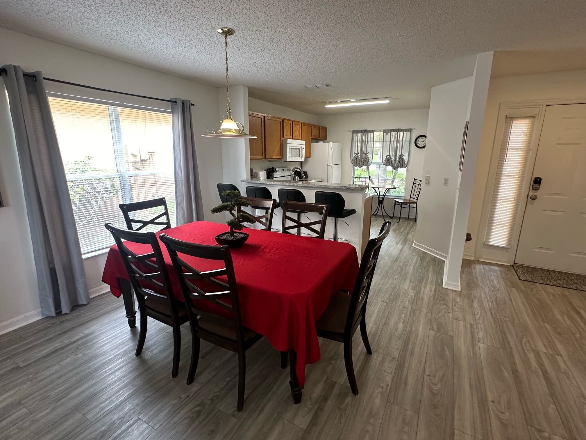A dining area with a red tablecloth, wooden chairs, and a bonsai tree centerpiece.