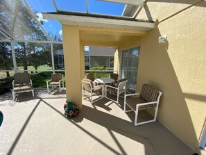 A covered patio with outdoor furniture, a pool, and a view of a house in the background. - Golf Course Views, South Facing Pool Villa (Haines City)