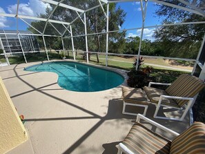 A covered outdoor swimming pool with lounge chairs and a view of the surrounding landscape. - Golf Course Views, South Facing Pool Villa (Haines City)