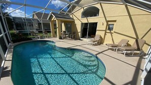 A swimming pool with clear water, surrounded by lounge chairs and a covered patio area. - Golf Course Views, South Facing Pool Villa (Haines City)