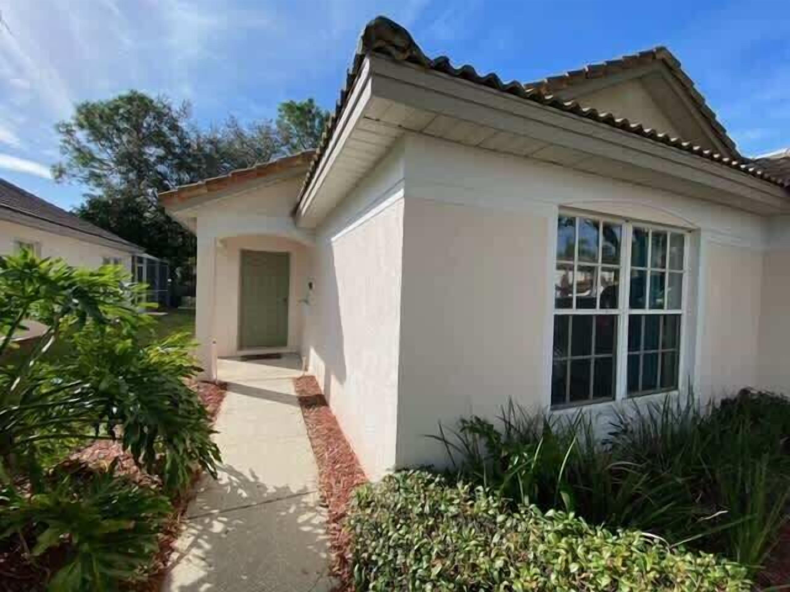 A single-story house with a white exterior, a tiled roof, and a front entrance.