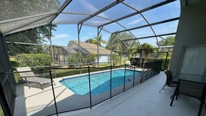 Piscina esterna coperta con vista libera sui dintorni, inclusa una casa e vegetazione.