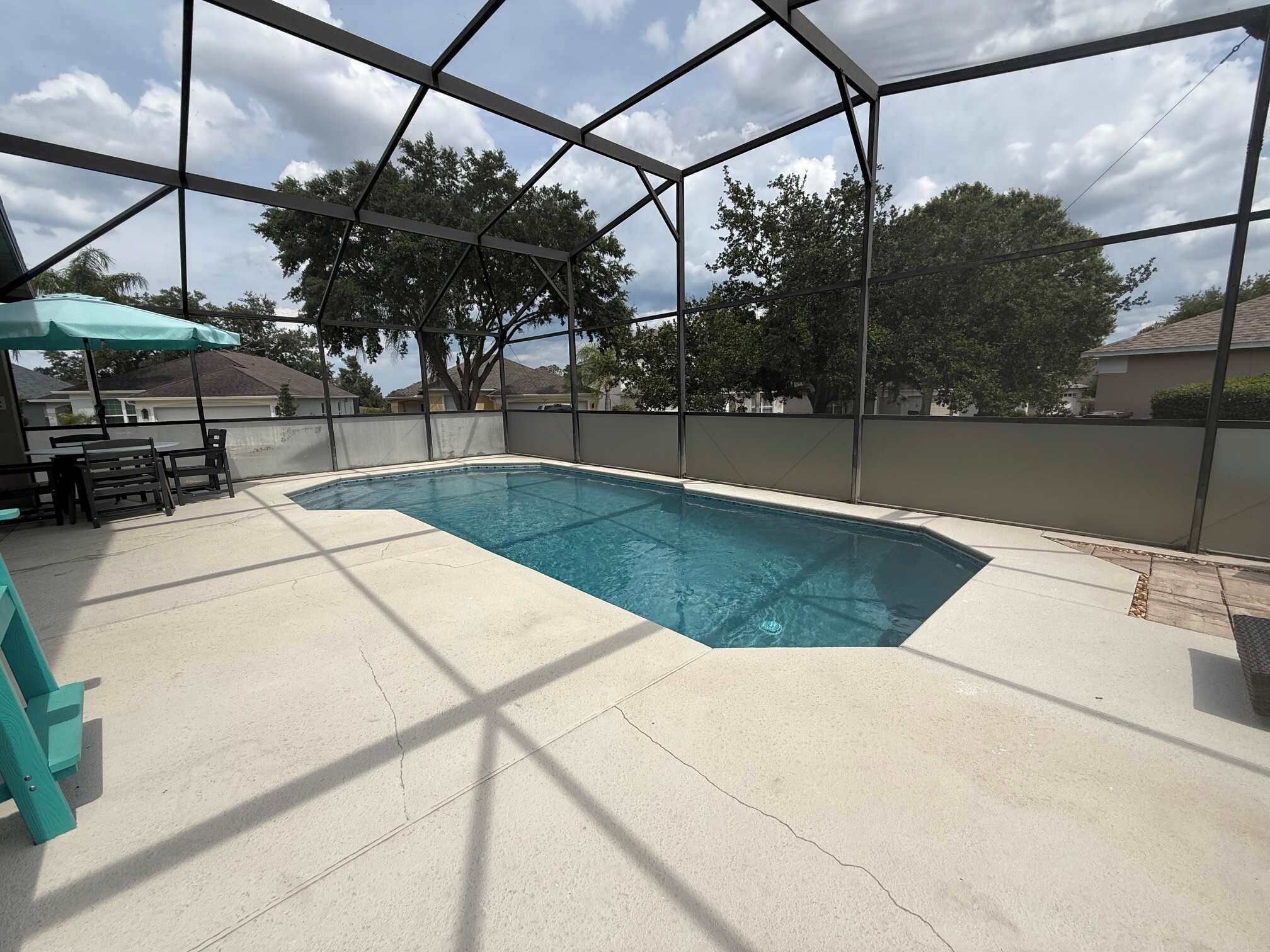 A swimming pool with a covered patio area, including a table and chairs.
