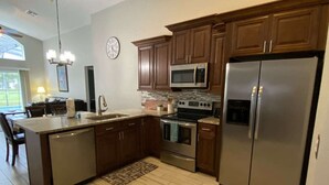 A modern kitchen with dark wood cabinets, stainless steel appliances, and a large island. - Southern Dunes Villa, Upgraded, Golf Views (Haines City)