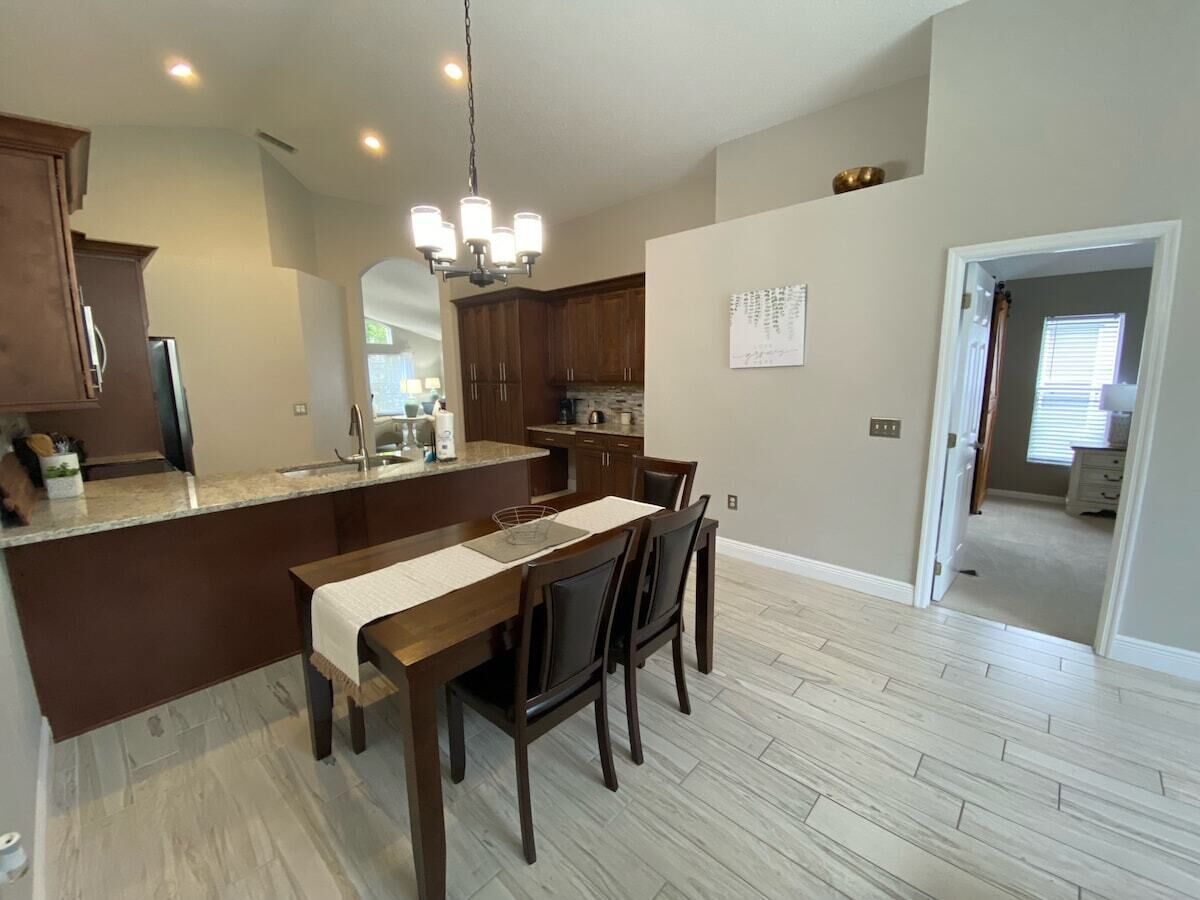 A modern kitchen with a dining area, wooden cabinets, and a chandelier.