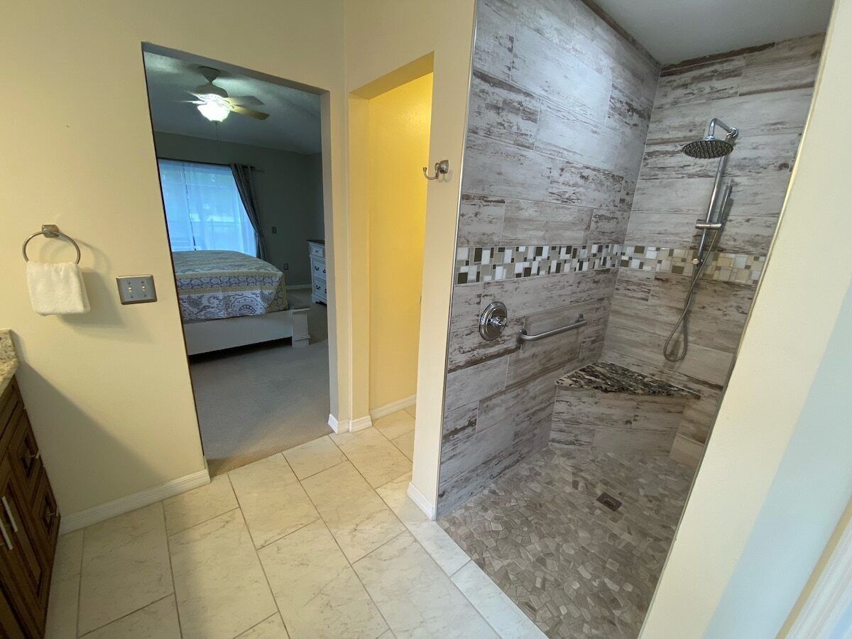 A bathroom with a shower, a toilet, and a sink. There is a towel hanging on the wall.