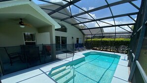 An indoor swimming pool with a glass ceiling, surrounded by a poolside area with chairs and a table. - Southern Dunes Villa, Upgraded, Golf Views (Haines City)