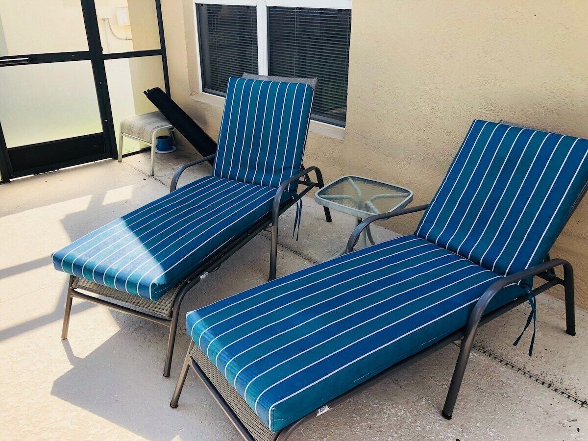 A sunlit outdoor seating area with two lounge chairs and a small table.
