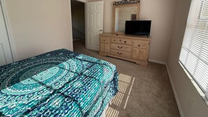 A bedroom with a bed, dresser, mirror, and a door leading to another room. - Southern Dunes Condo, Golf Course Views (Haines City)