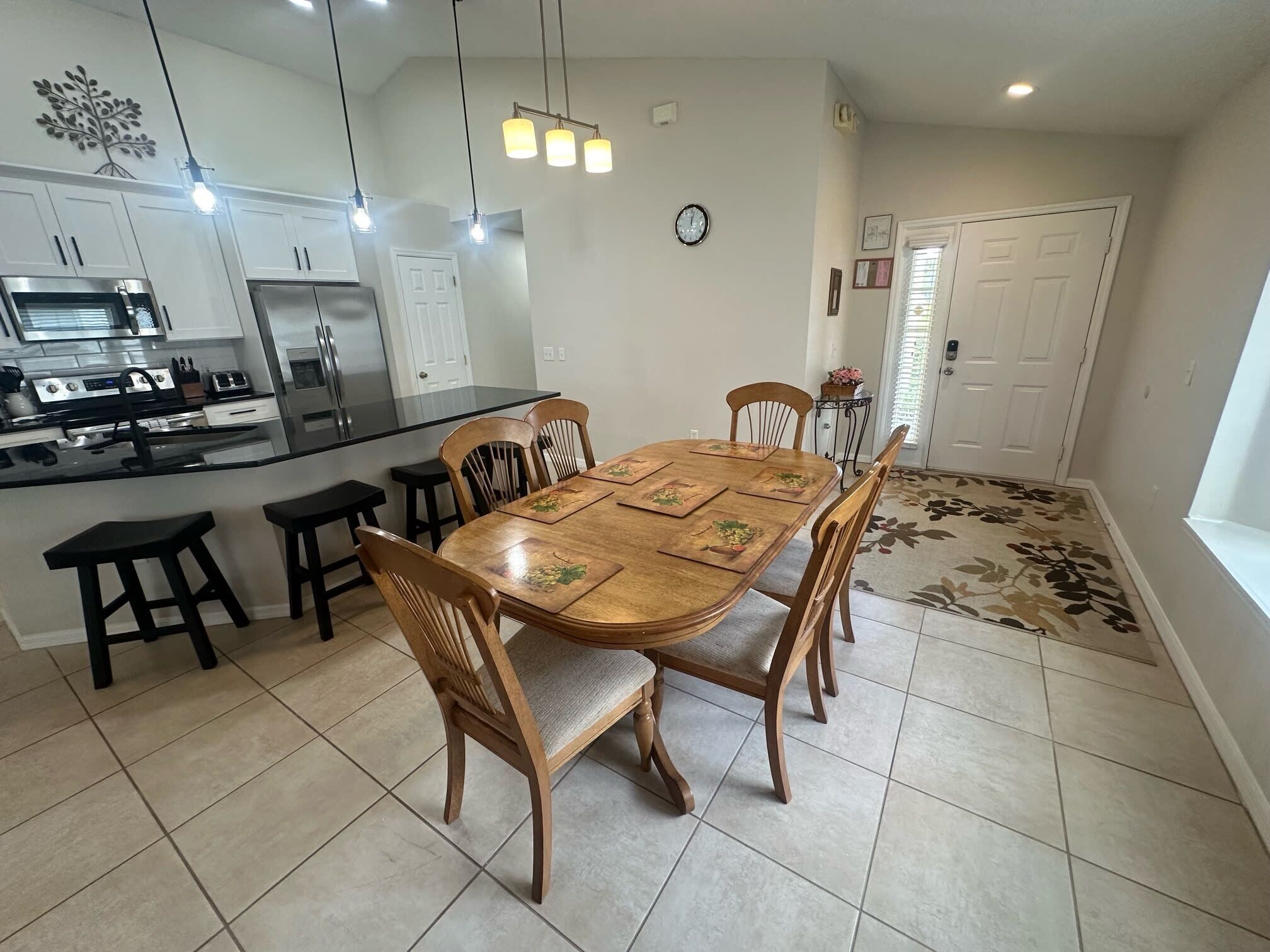 Una cocina moderna con una isla central, electrodomésticos integrados y un comedor con sillas de madera y una mesa.