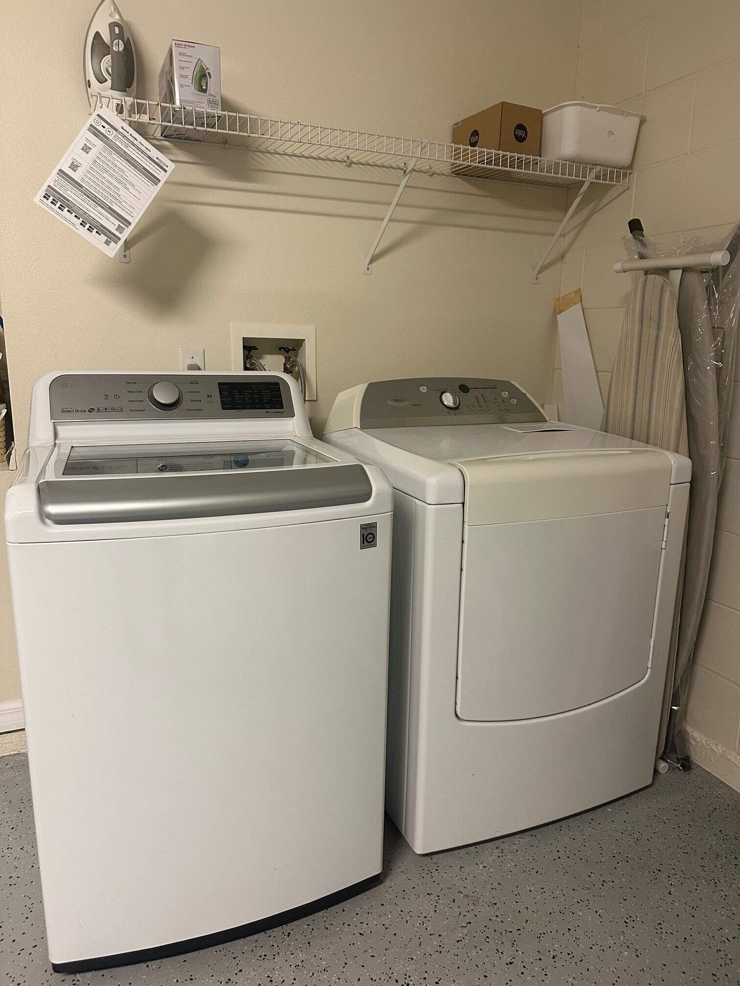 A laundry area with two white front-loading washing machines and a metal drying rack.