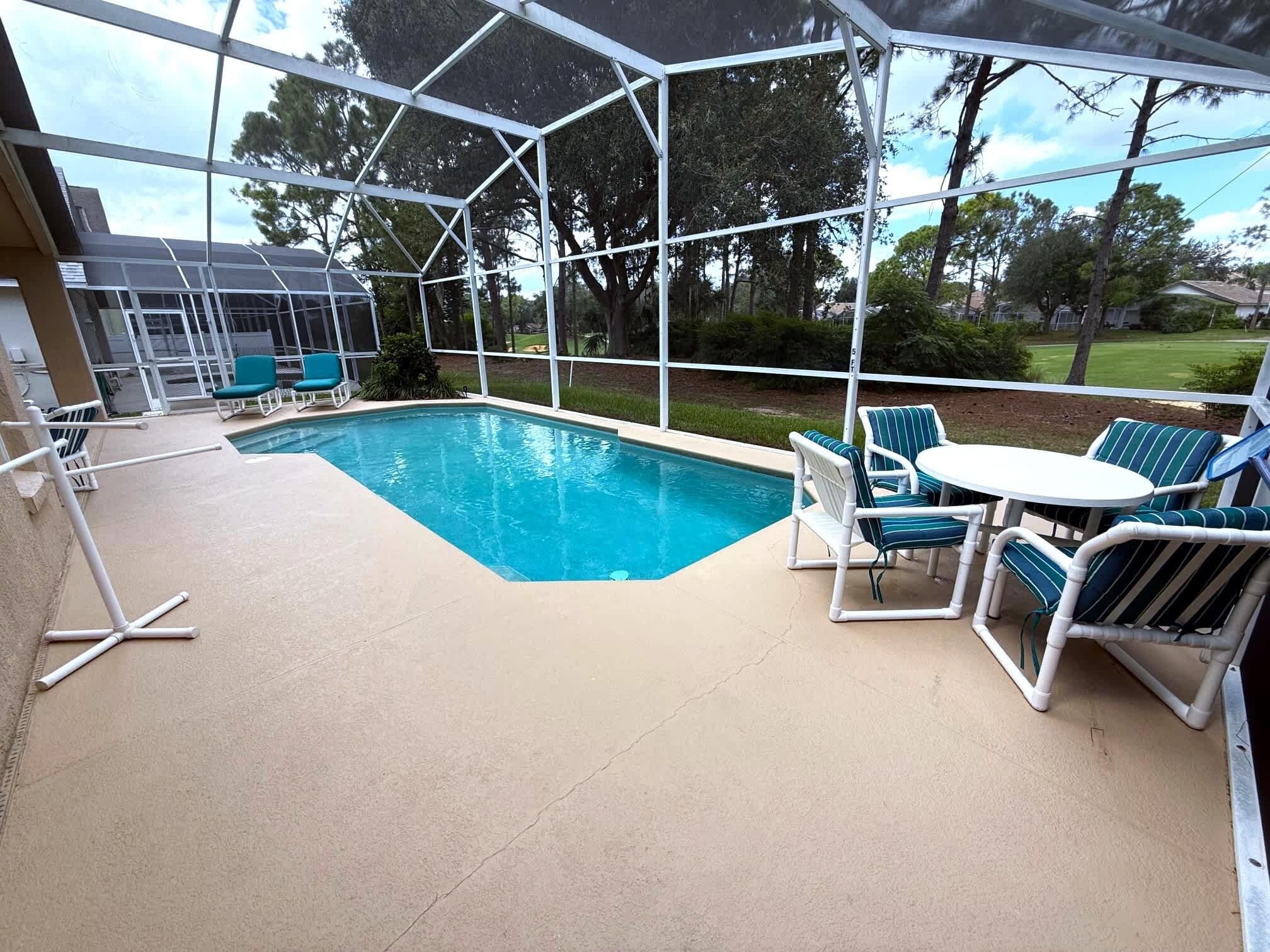 A covered outdoor swimming pool with a view of a residential area, including houses and trees.