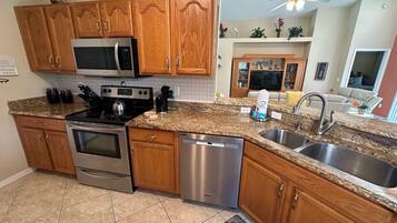 A modern kitchen with wooden cabinets, stainless steel appliances, granite countertops, and a built-in dishwasher.