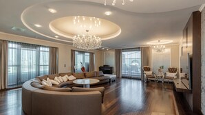 A spacious living room with a large L-shaped sectional sofa, a round coffee table, and a chandelier. - Luxurious Penthouse for Rent Bucharest - Marque De Lago (București)