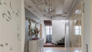 A modern interior with a chandelier, a white dresser, and a staircase leading to an upper level. - Luxurious Penthouse for Rent Bucharest - Marque De Lago (București)