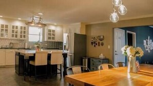 Una cocina amplia con comedor, que incluye una mesa y sillas de madera, un refrigerador y una lámpara colgante.