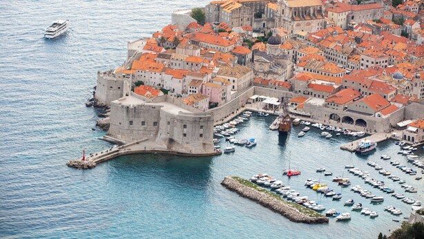 An aerial view of a historic coastal town with a fortified castle, a harbor filled with boats, and a prominent church with a dome. - Charming 2-bedroom apartment with WiFi, AC in lovely Dubrovnik (Dubrovnik)