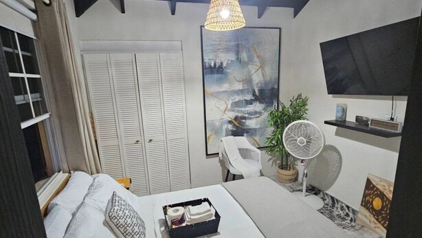 Un dormitorio moderno con cama, mesita de noche, lámpara y un cuadro en la pared.