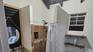 Un baño pequeño con ducha, inodoro y lavabo.