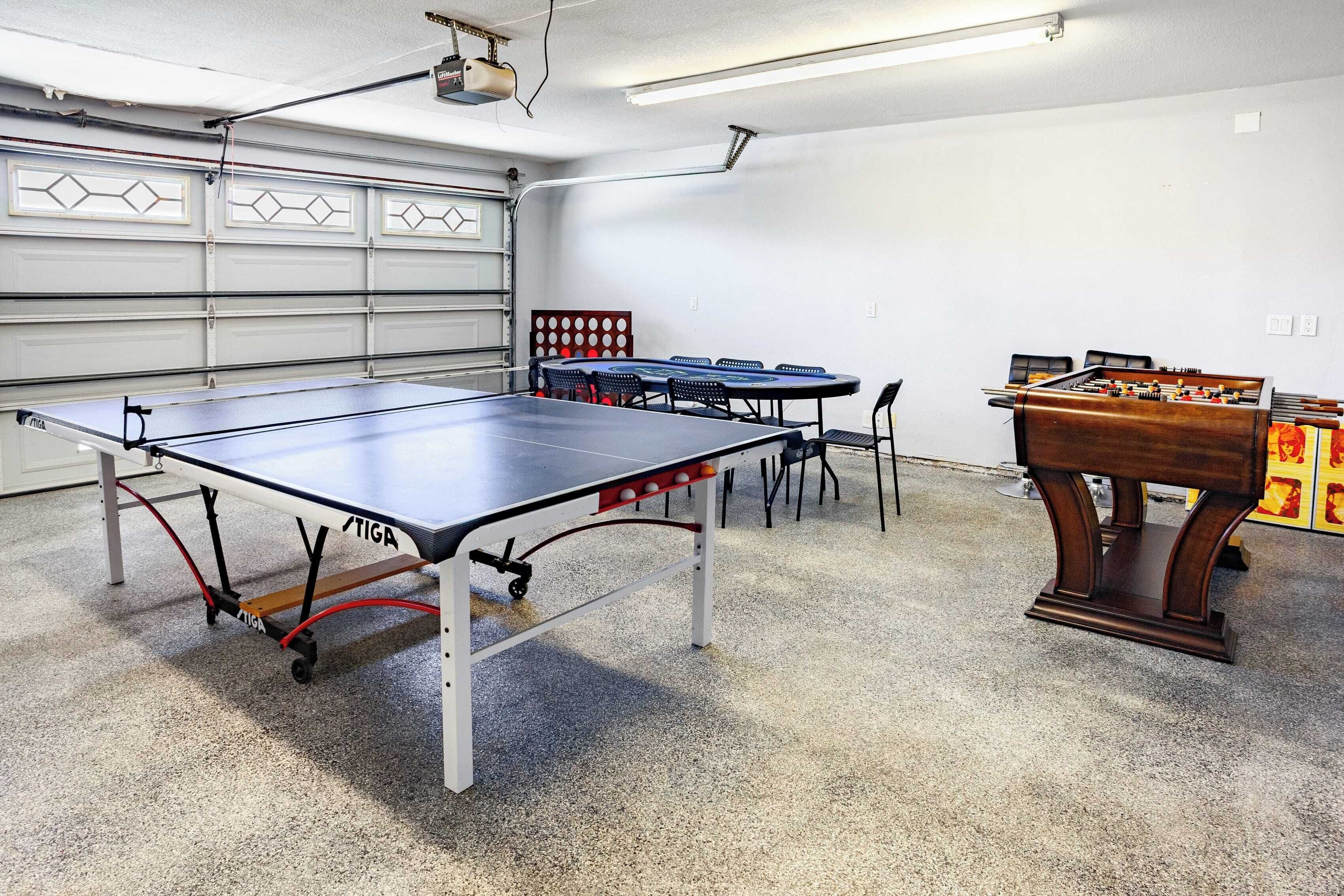 A room with a ping pong table, a foosball table, and a table tennis table.