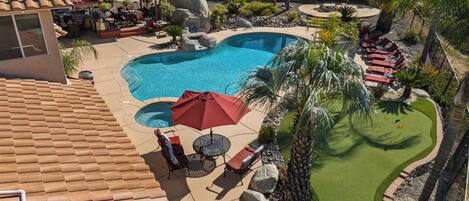 A backyard with a swimming pool, lounge chairs, and a patio area.