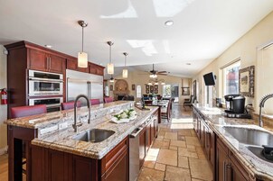 A spacious kitchen with granite countertops, stainless steel appliances, and pendant lighting.